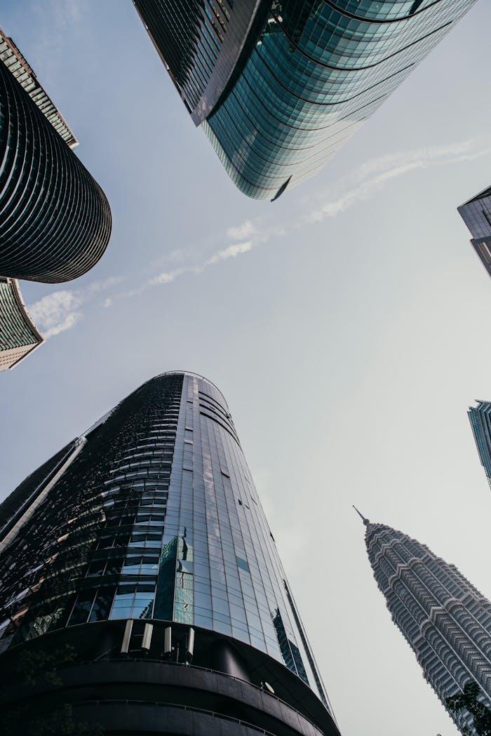 Low angle view of modern skyscrapers in Kuala Lumpur with Petronas Twin Towers visible.