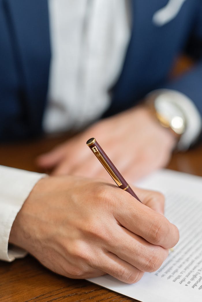 Close-up of a hand signing a business contract with a fountain pen.
